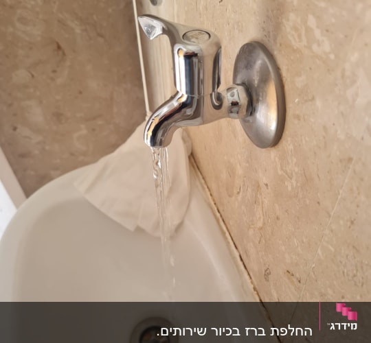 ברז מים זורם בכיור עם קיר אבן